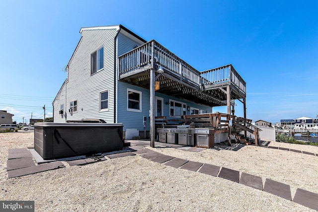 back of house with a wooden deck and a hot tub