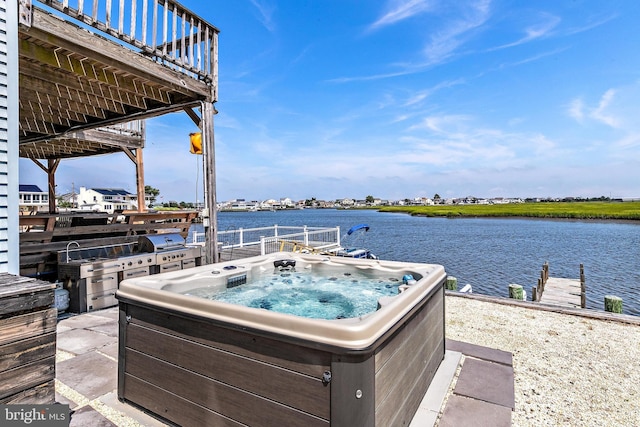 view of patio / terrace featuring a water view and a hot tub