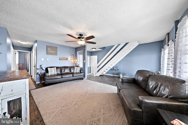 living room with a textured ceiling, dark wood-type flooring, and ceiling fan