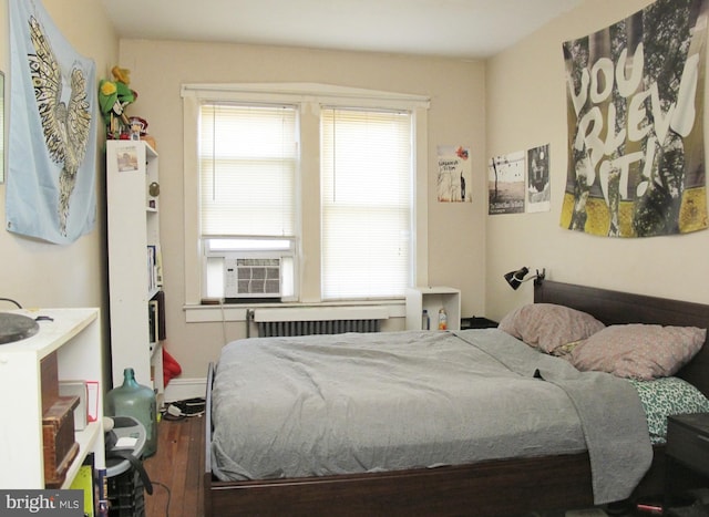 bedroom with cooling unit, radiator, dark hardwood / wood-style flooring, and multiple windows