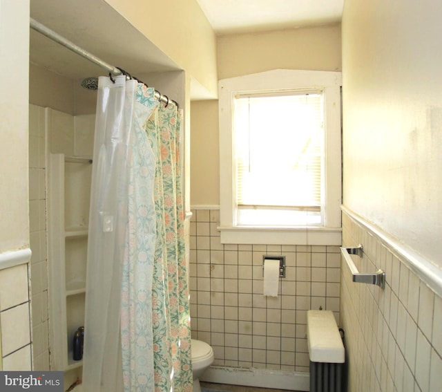 bathroom featuring toilet, a shower with shower curtain, and tile walls