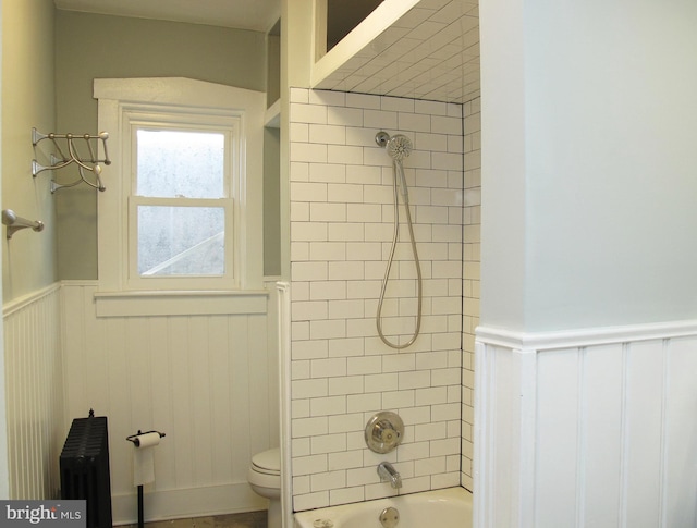 bathroom featuring radiator, toilet, and tiled shower / bath