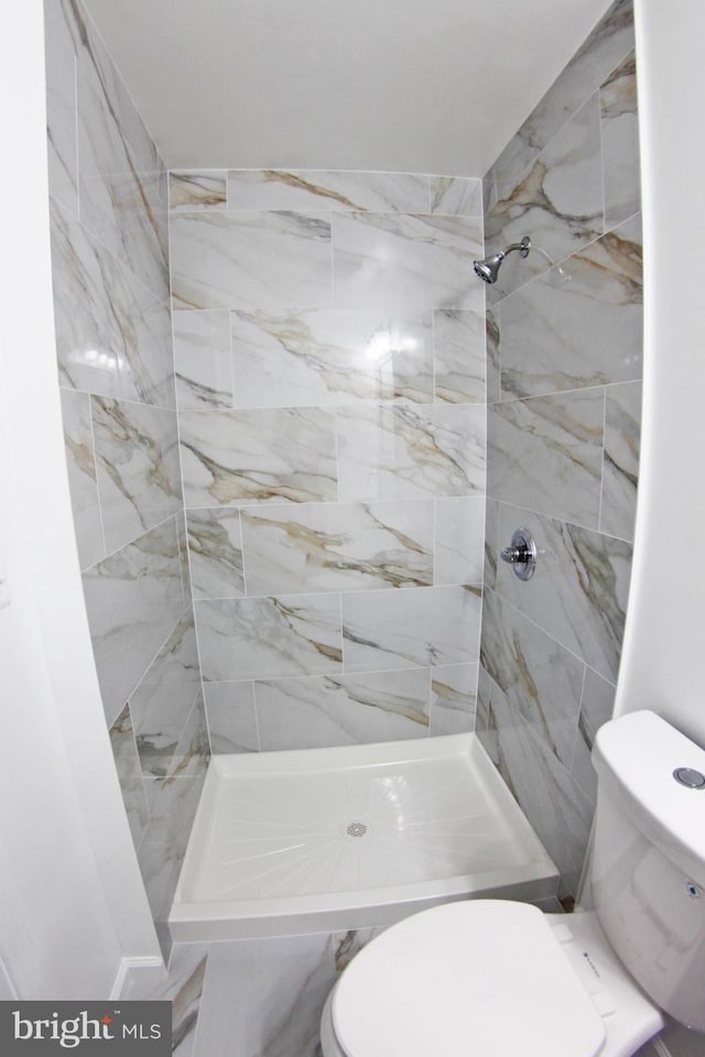 bathroom with tiled shower and toilet