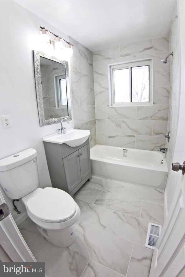 full bathroom featuring tiled shower / bath combo, vanity, and toilet