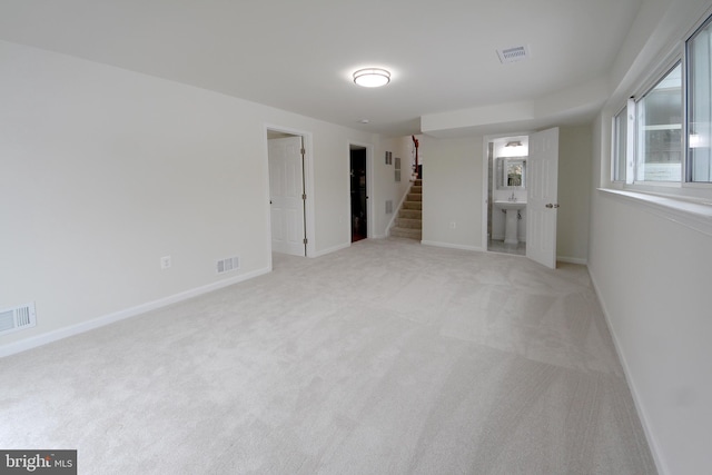 spare room with sink and light colored carpet