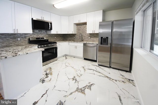 kitchen featuring light stone counters, tasteful backsplash, white cabinetry, and stainless steel appliances