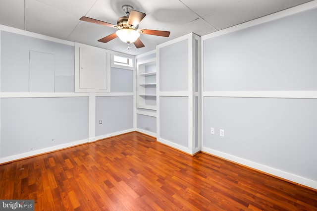 empty room featuring baseboards, ceiling fan, built in features, and wood finished floors