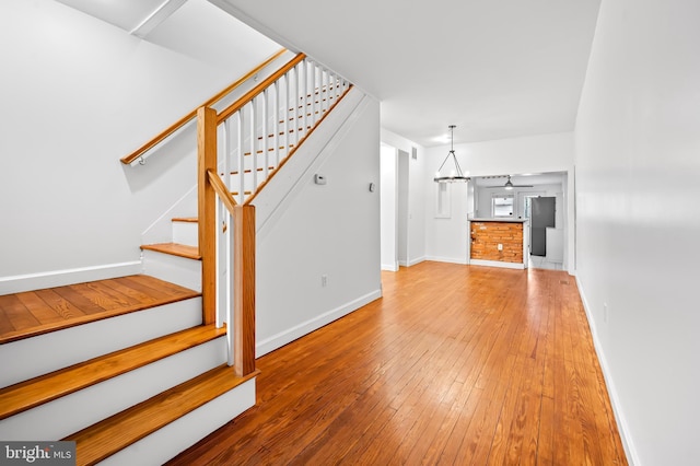 unfurnished living room featuring stairs, baseboards, and hardwood / wood-style floors