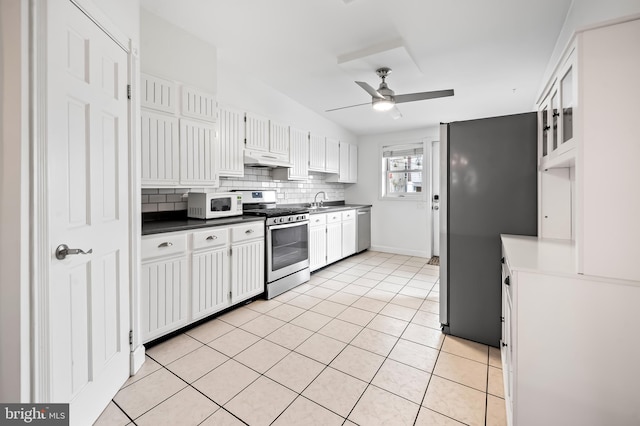 kitchen with stainless steel appliances, backsplash, white cabinets, light tile patterned flooring, and under cabinet range hood