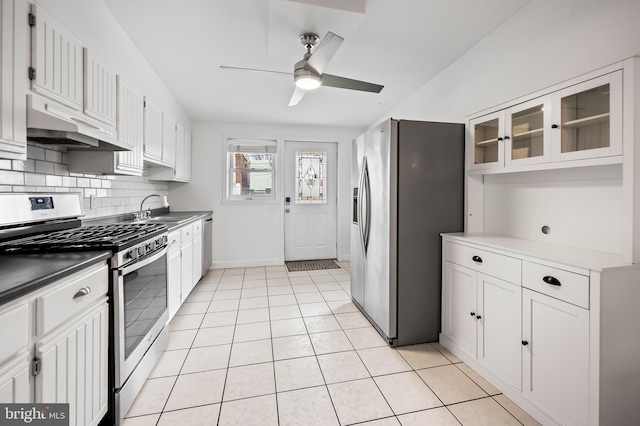 kitchen with light tile patterned floors, appliances with stainless steel finishes, a sink, under cabinet range hood, and backsplash