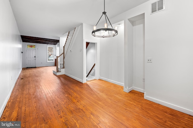 interior space featuring baseboards, visible vents, stairway, hardwood / wood-style floors, and an inviting chandelier