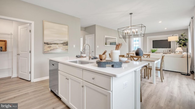 kitchen featuring sink, white cabinetry, light hardwood / wood-style floors, stainless steel dishwasher, and a center island with sink