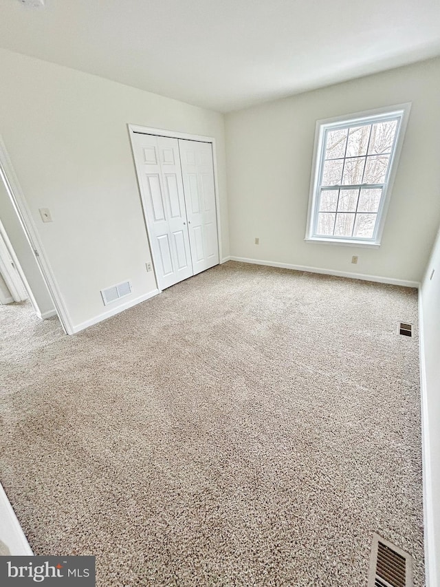 unfurnished bedroom featuring baseboards, visible vents, a closet, and carpet floors