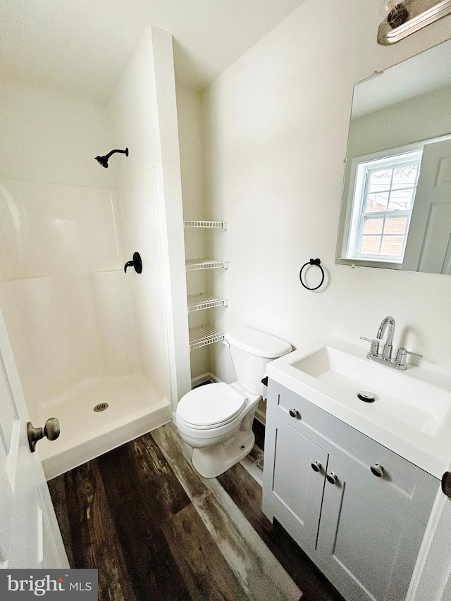 full bathroom with vanity, wood finished floors, toilet, and a shower