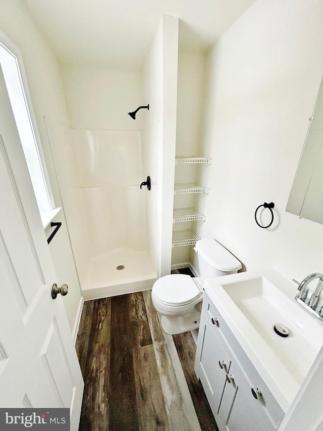 full bathroom featuring toilet, vanity, a shower, and wood finished floors