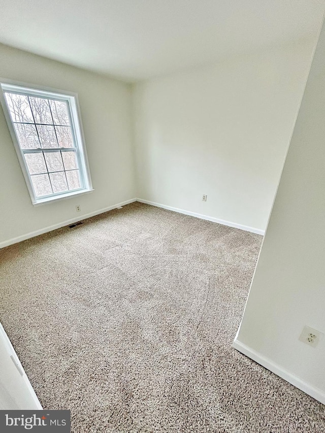 spare room with baseboards, visible vents, and carpet floors