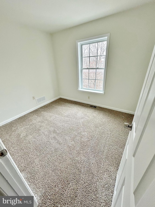 carpeted spare room featuring visible vents and baseboards