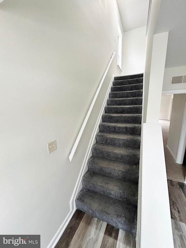 stairs featuring visible vents, baseboards, and wood finished floors