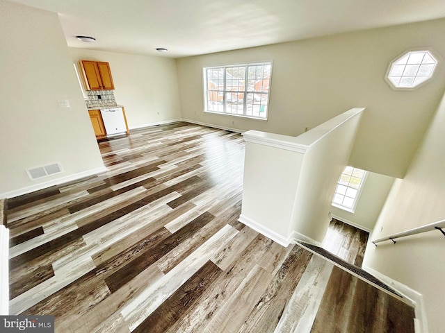 unfurnished living room featuring visible vents, baseboards, and wood finished floors