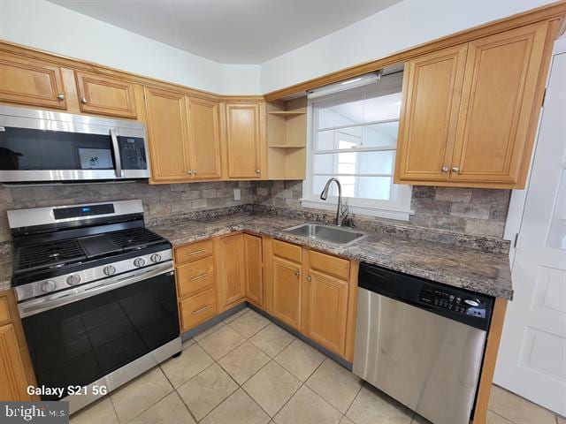 kitchen featuring stainless steel appliances, sink, dark stone countertops, tasteful backsplash, and light tile patterned floors