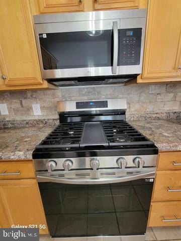 kitchen with stainless steel appliances, backsplash, and light stone countertops