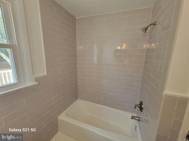 bathroom with tile walls and tiled shower / bath combo