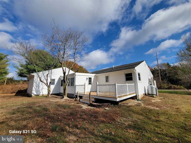 back of property with a yard and a wooden deck