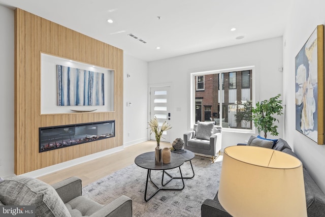 living room with a large fireplace and light hardwood / wood-style floors