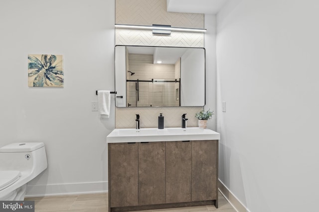 bathroom with toilet, a shower with door, decorative backsplash, and vanity