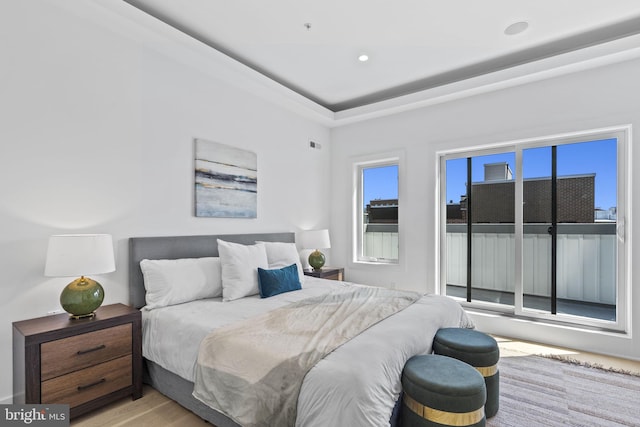 bedroom with a tray ceiling and light hardwood / wood-style flooring