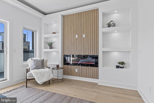 living area with built in shelves and hardwood / wood-style flooring