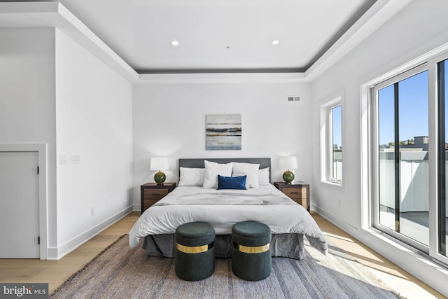 bedroom featuring a raised ceiling and light hardwood / wood-style flooring