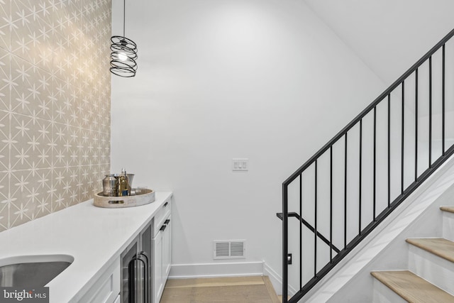 clothes washing area with light wood-type flooring and wine cooler