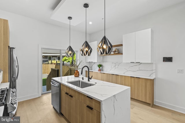 kitchen featuring a center island with sink, appliances with stainless steel finishes, sink, white cabinetry, and decorative light fixtures