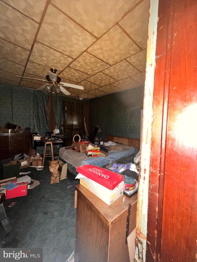 interior space featuring ceiling fan, wooden walls, and carpet flooring