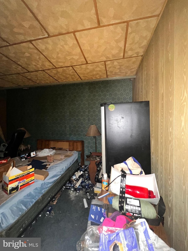 bedroom featuring stainless steel fridge and wooden walls