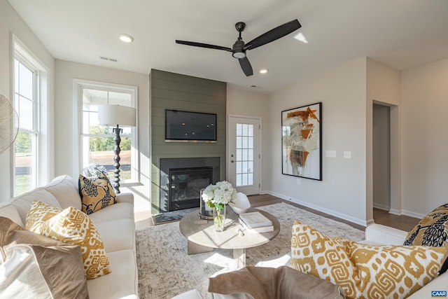 living room featuring a large fireplace, ceiling fan, and light hardwood / wood-style flooring