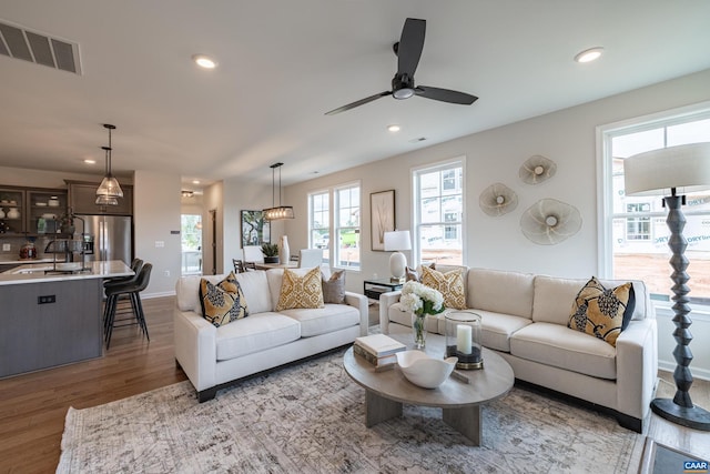 living room with sink, ceiling fan, and light hardwood / wood-style flooring