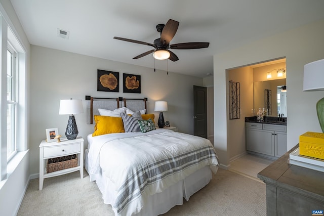 carpeted bedroom featuring ensuite bathroom, ceiling fan, and sink