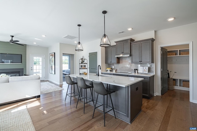 kitchen with a breakfast bar area, hanging light fixtures, ceiling fan, decorative backsplash, and sink