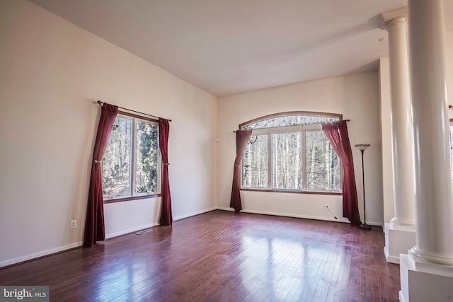 spare room with decorative columns, dark wood-type flooring, and a healthy amount of sunlight