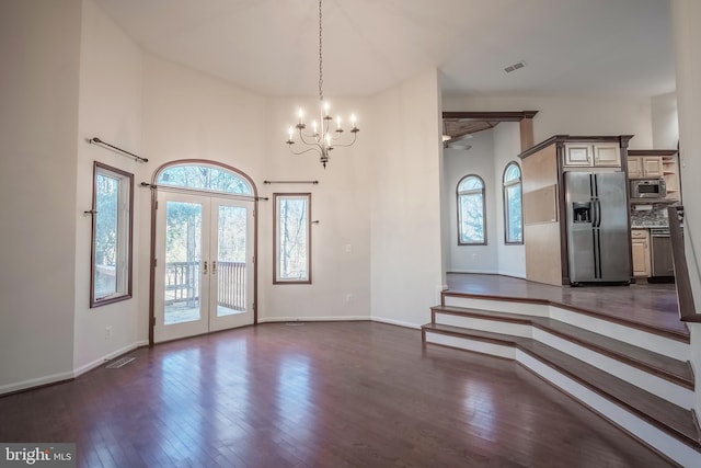 entrance foyer with an inviting chandelier, dark hardwood / wood-style flooring, and french doors