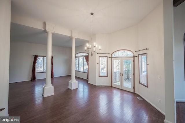 interior space featuring decorative columns, dark hardwood / wood-style floors, french doors, and an inviting chandelier