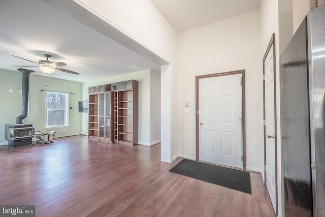 foyer with ceiling fan, a wood stove, and dark hardwood / wood-style floors