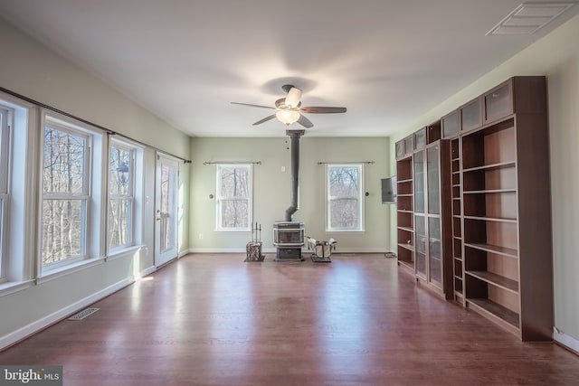 interior space featuring dark wood-type flooring, ceiling fan, and a wood stove