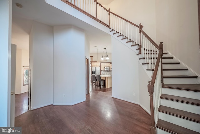 staircase featuring a high ceiling, an inviting chandelier, and hardwood / wood-style floors