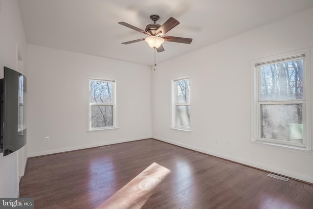 unfurnished living room with dark wood-type flooring, a wealth of natural light, and ceiling fan