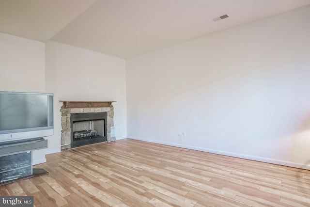 unfurnished living room featuring light hardwood / wood-style floors and a stone fireplace