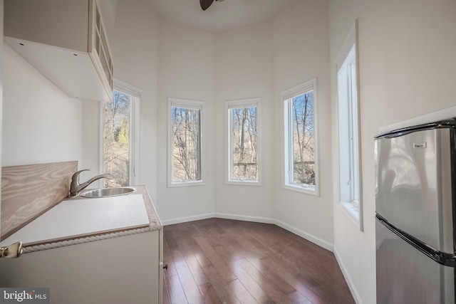 kitchen featuring ceiling fan, dark hardwood / wood-style floors, a towering ceiling, sink, and stainless steel fridge