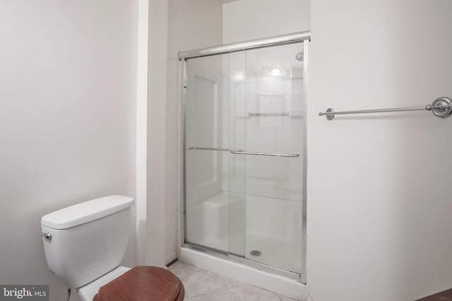 bathroom featuring toilet, tile patterned flooring, and a shower with door